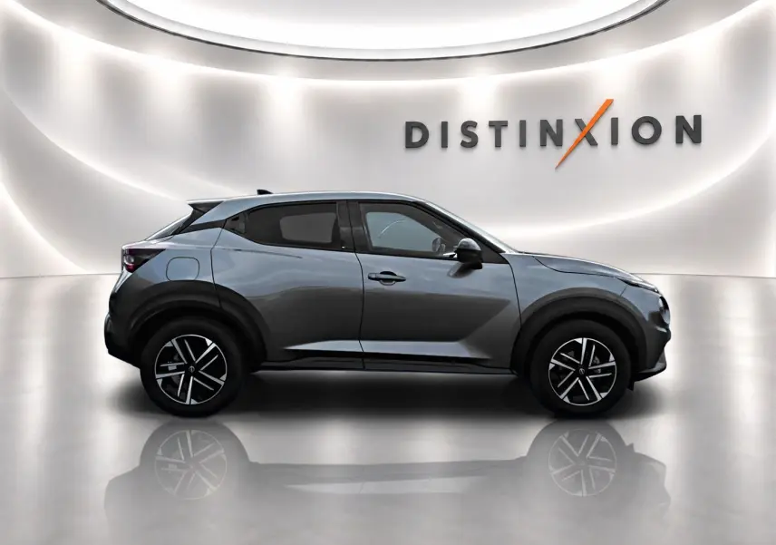 Profil droit du Nissan Juke gris 2025 avec jantes alliage noires et toit noir dans un studio lumineux.