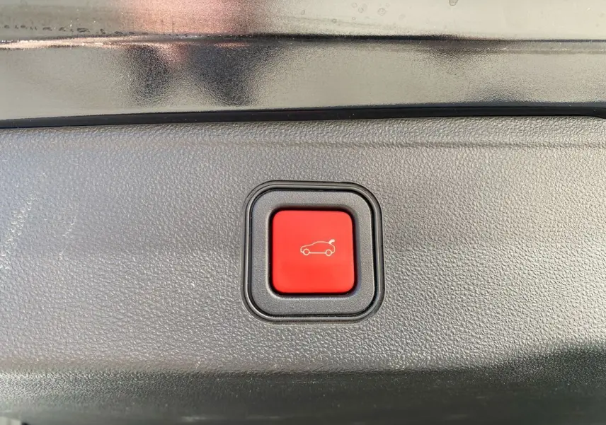 Bouton rouge d'ouverture électrique du coffre sur un Jeep Avenger noir électrique 2023, vue rapprochée intérieure.