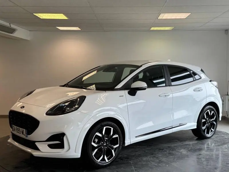 Ford Puma blanc glacier en 3/4 avant droit avec jantes alliage noires et toit noir dans un showroom intérieur.