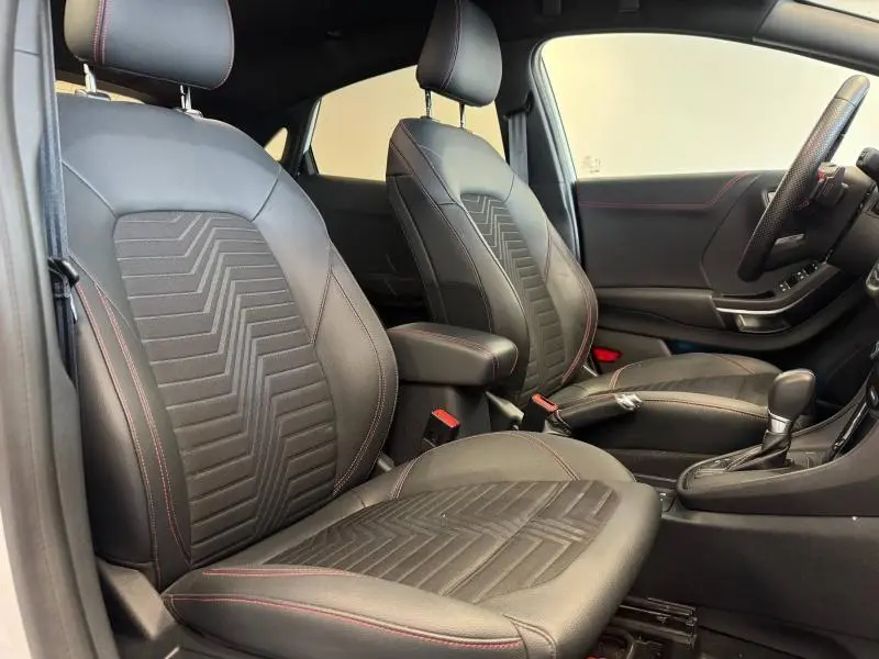 Vue intérieure côté conducteur du Ford Puma 2022, sièges noirs avec surpiqûres rouges et volant multifonction sport.