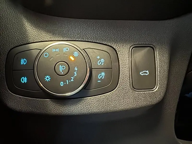 Gros plan sur les commandes d'éclairage et ouverture du hayon du Ford Puma blanc, intérieur noir texturé.