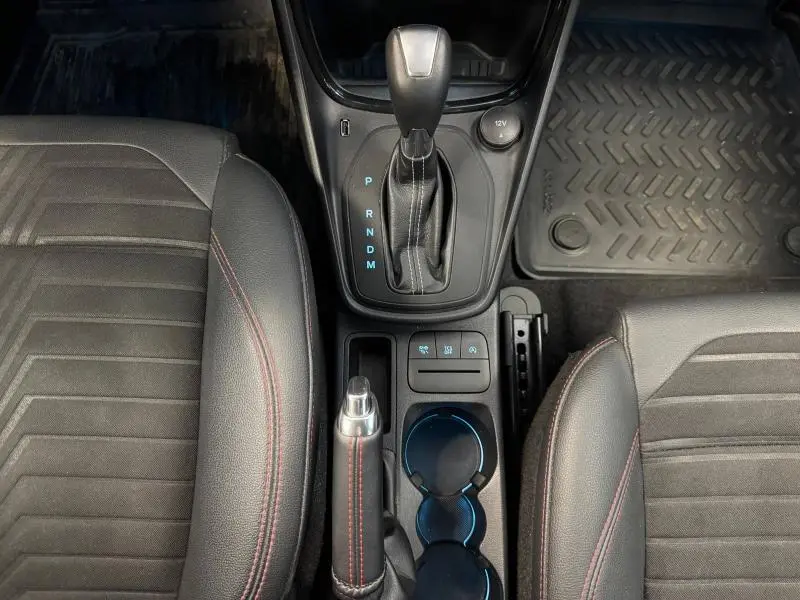 Vue plongeante sur la console centrale avec levier de vitesses automatique et sièges noirs à surpiqûres rouges du Ford Puma blanc Glacier 2022.