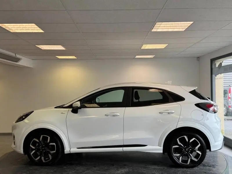 Ford Puma blanc glacier vu de profil côté gauche, avec jantes alliage noires et toit incliné en arrière.