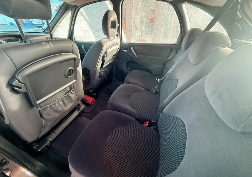 Vue intérieure arrière montrant les sièges noirs en tissu du Citroën Xsara Picasso 2009 beige.