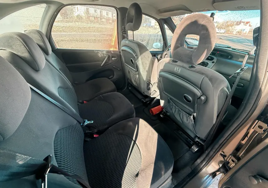 Vue intérieure arrière droite du Citroën Xsara Picasso 2009, sièges tissu noir et dossier avant avec tablette intégrée.