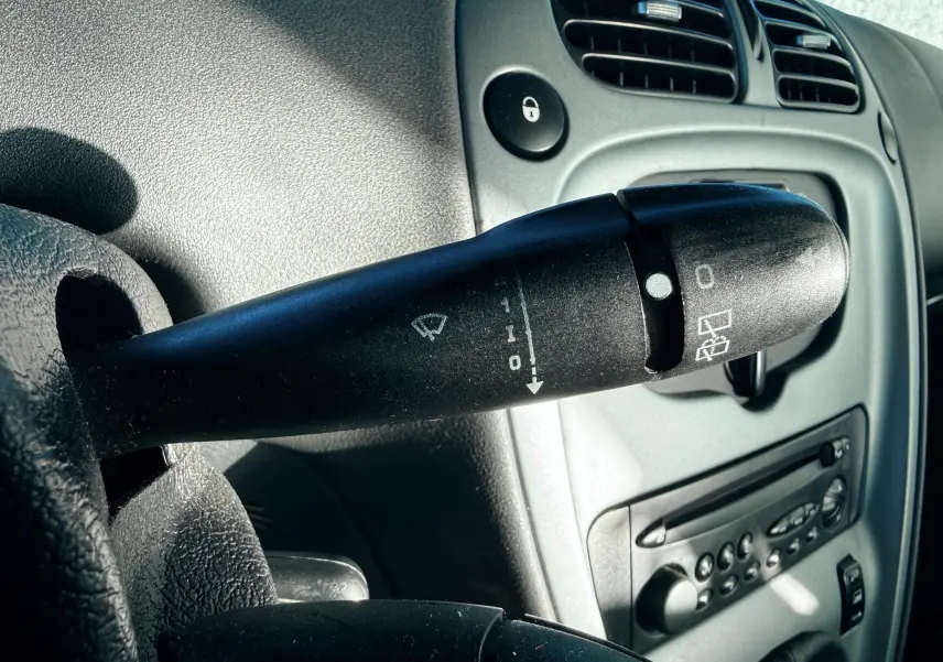 Gros plan sur la commande d’essuie-glace côté gauche du tableau de bord gris clair d’une Citroën Xsara Picasso.