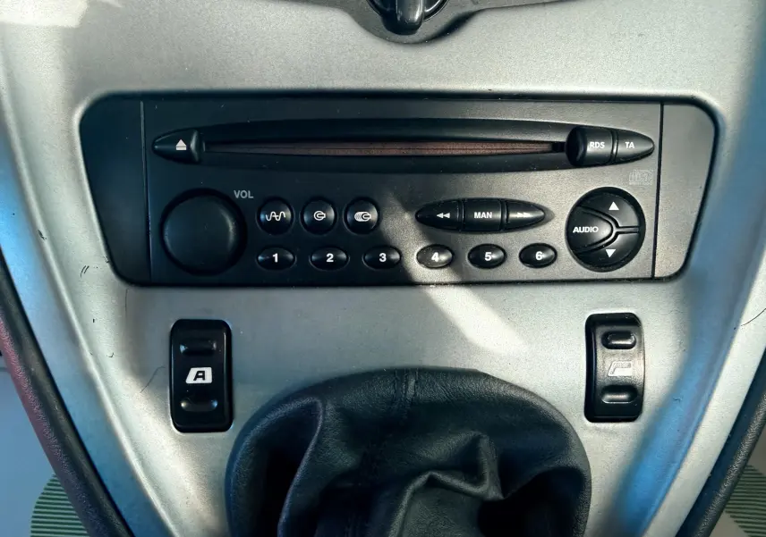 Vue rapprochée de la console centrale grise avec autoradio et levier de vitesse en cuir noir d'une Citroën Xsara Picasso beige.