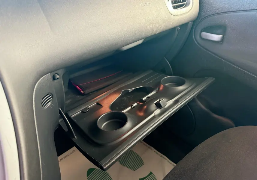 Intérieur de la Citroën Xsara Picasso beige 2009, vue sur la boîte à gants ouverte côté passager avec porte-gobelets intégrés.