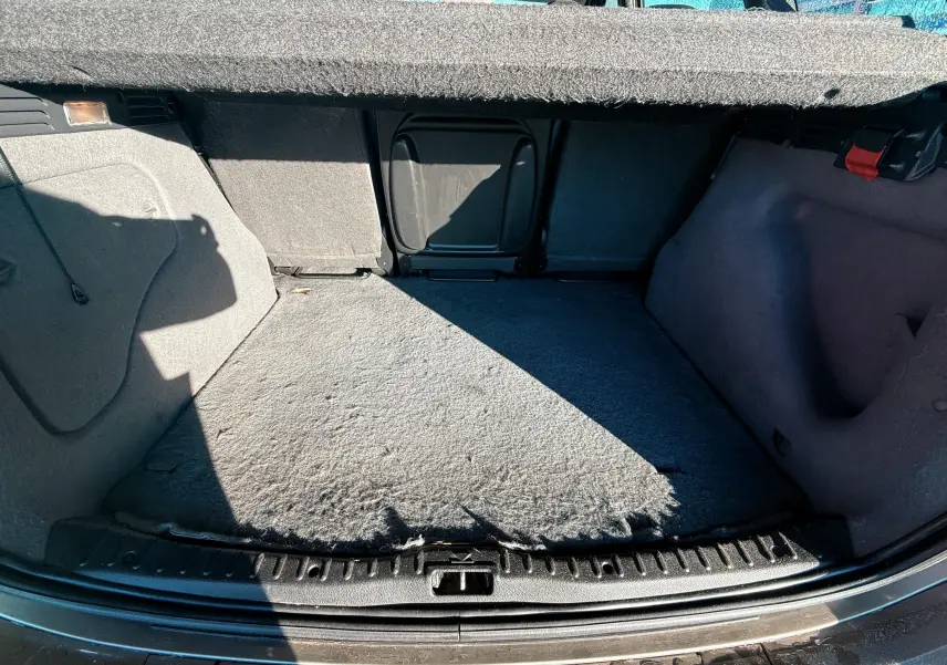 Vue intérieure du coffre beige du Citroën Xsara Picasso 2009, montrant l'espace de chargement et la moquette usée.