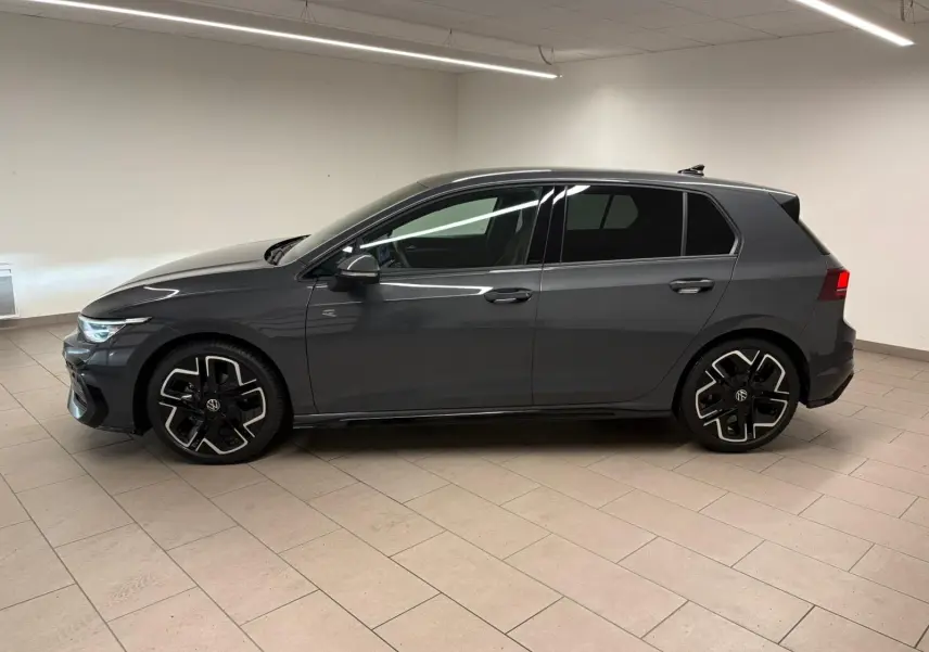 Vue de profil côté gauche d'une Volkswagen Golf 1.5 eTSI 150 DSG7 R-Line Edition gris dauphin en intérieur, avec jantes spécifiques R-Line.