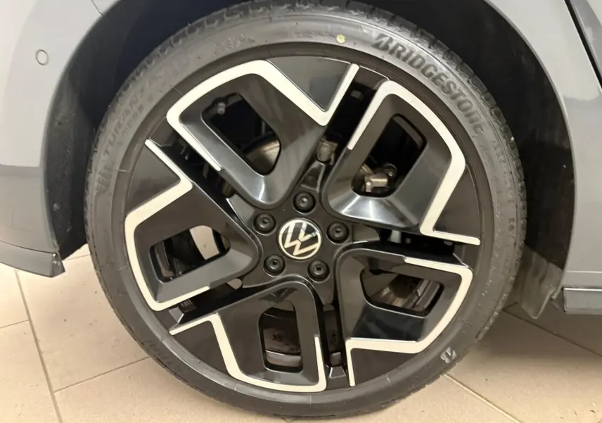 Gros plan sur la jante noire et argentée d'une Volkswagen Golf Gris Dauphin, côté avant droit.