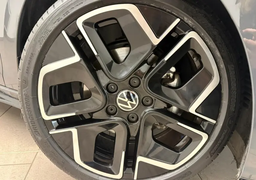 Gros plan sur la jante avant droite noire et argentée d'une Volkswagen Golf Gris Dauphin 2025 R-Line Edition.