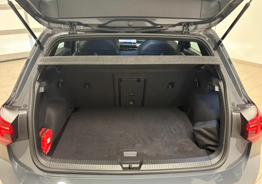 Coffre ouvert vu de l'arrière d'une Volkswagen Golf gris dauphin, avec cache-bagages et intérieur spacieux.