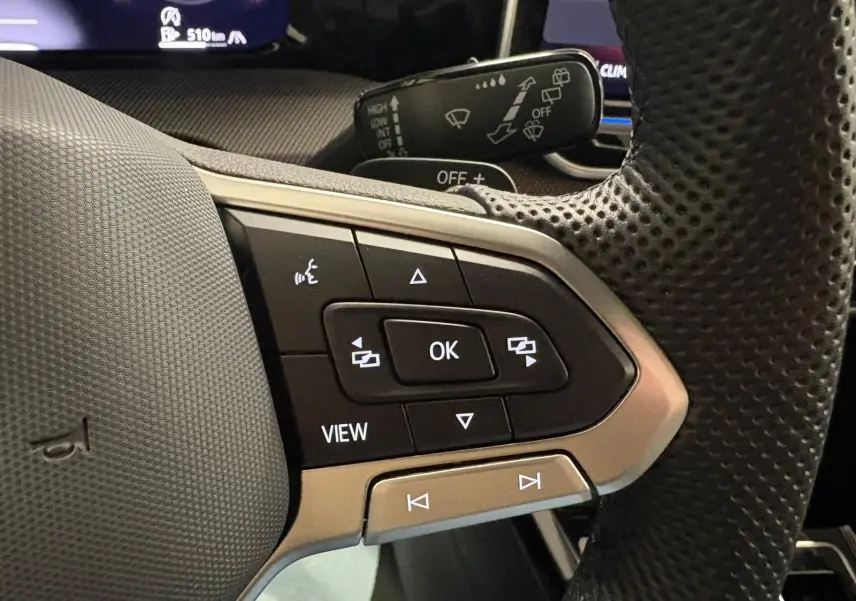 Gros plan sur les commandes multifonctions à droite du volant perforé d’une Volkswagen Golf Gris Dauphin 2025.