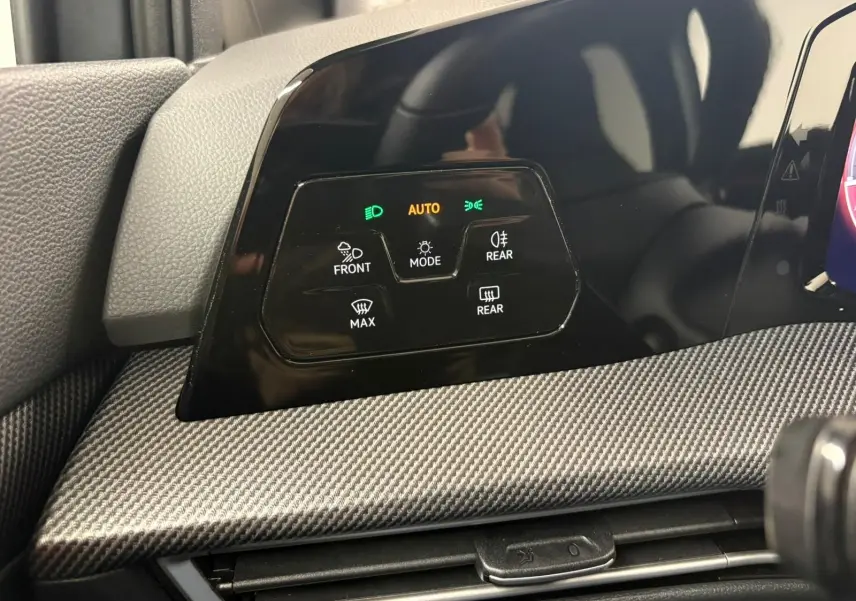 Détail du tableau de bord avec commandes d'éclairage et finition carbone dans une Volkswagen Golf Gris Dauphin 2025.