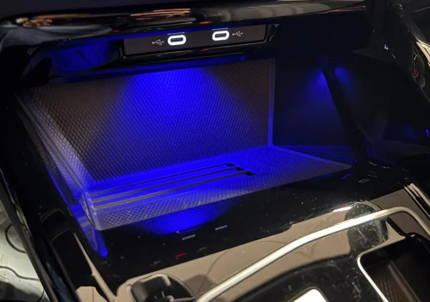 Gros plan sur le rangement central éclairé en bleu avec ports USB-C dans une Volkswagen Golf Gris Dauphin 2025.