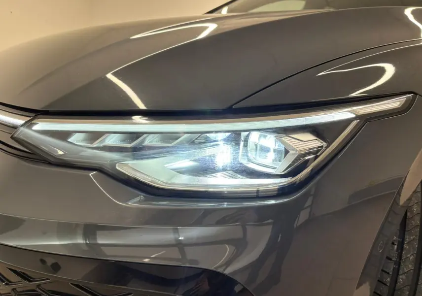 Gros plan sur le phare avant droit d’une Volkswagen Golf 1.5 eTSI Gris Dauphin avec éclairage LED distinctif.
