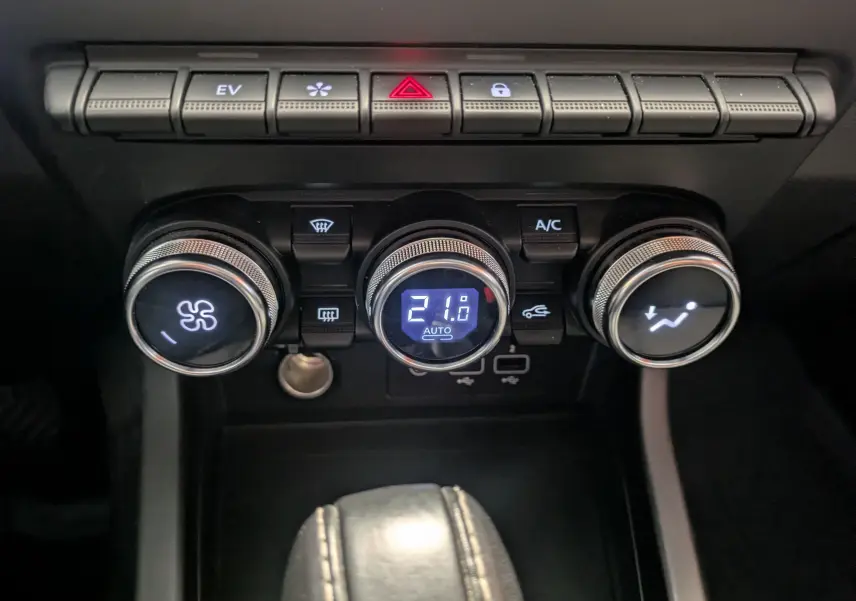 Gros plan sur les commandes de climatisation du tableau de bord du Renault Arkana noir, avec affichage digital à 21°C.