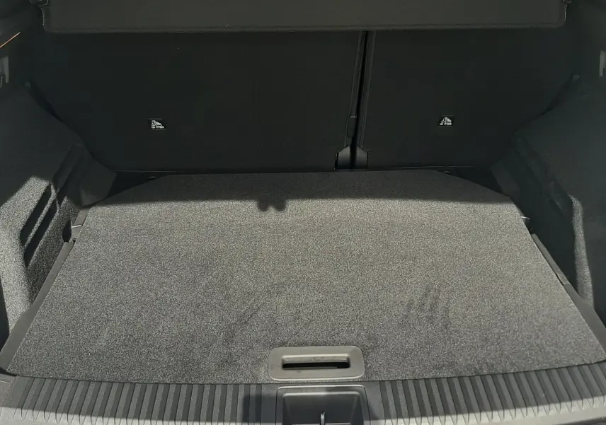 Vue intérieure du coffre ouvert du Renault Austral blanc nacré, montrant le faux plancher et les finitions noires.