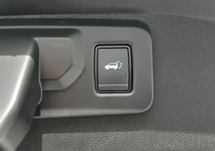 Bouton d'ouverture électrique du hayon sur la garniture intérieure d'un Renault Austral blanc nacré.