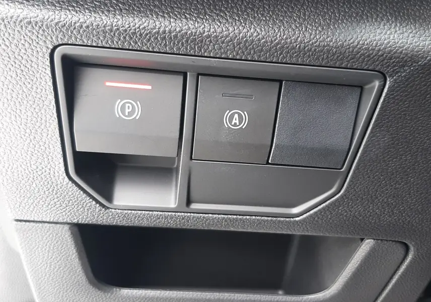 Gros plan sur les commandes noires du frein de parking électrique et de l'arrêt automatique du moteur dans un Renault Austral blanc nacré.