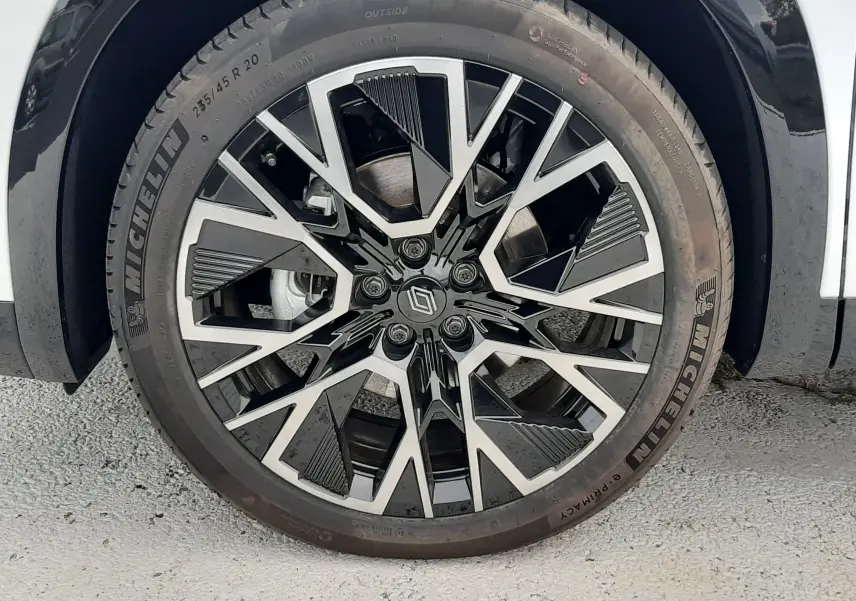 Gros plan sur la jante alliage 20'' noire et argentée du Renault Austral blanc nacré, avec pneu Michelin visible.