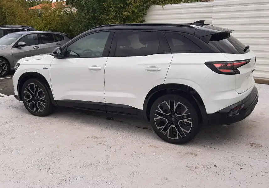 Renault Austral blanc nacré avec toit noir étoilé, vue de profil côté gauche, jantes alliage noires et détails hybrides.