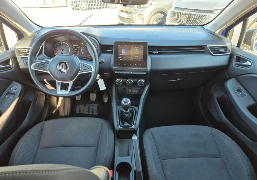 Vue intérieure avant de la Renault Clio V TCe 90 Equilibre 2023, tableau de bord noir avec écran tactile et boîte manuelle.