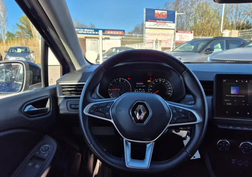 Vue intérieure centrée sur le volant de la Renault Clio bleu foncé 2023 avec tableau de bord et écran tactile visibles.