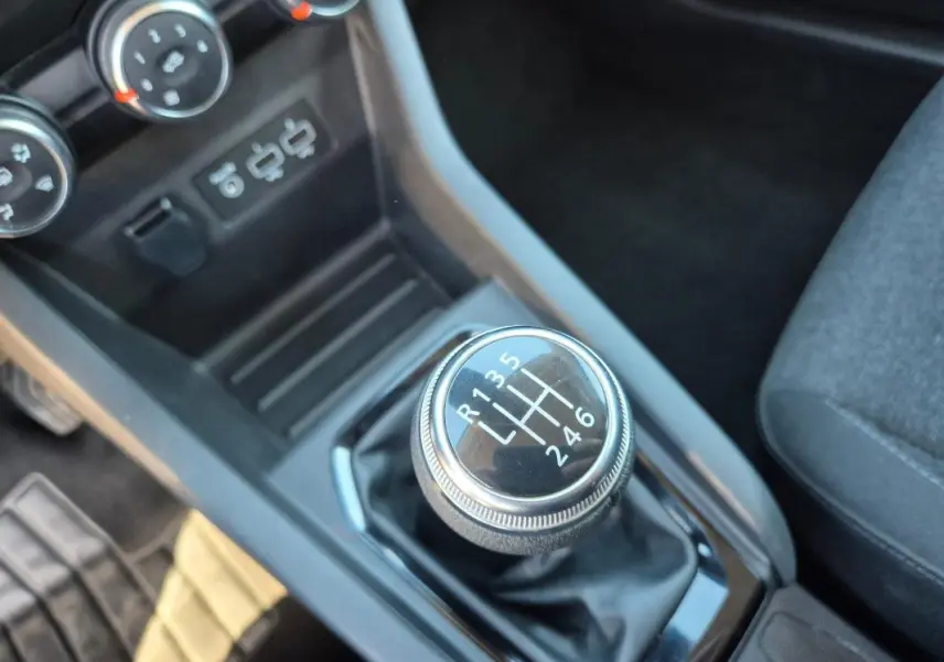 Gros plan sur le levier de vitesses manuel de la Renault Clio V TCe 90, entouré de la console noire et siège gris.