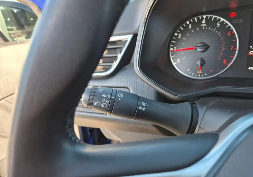 Gros plan sur le commodo des phares et clignotants côté gauche du volant d'une Renault Clio bleu foncé 2023.