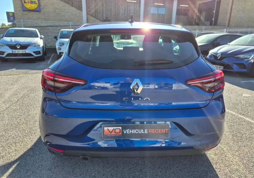 Vue arrière d'une Renault Clio bleu foncé 2023, avec feux arrière allumés et plaque "Véhicule récent" visible.