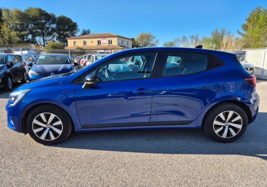 Profil latéral droit d'une Renault Clio bleu foncé 2023 garée en extérieur, avec jantes alliage distinctives.