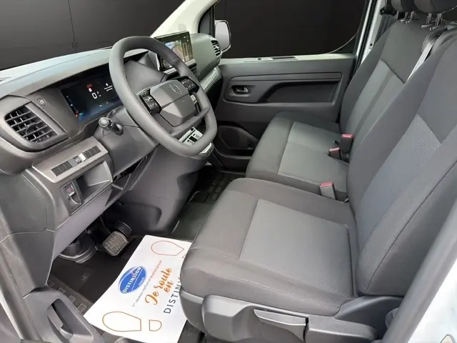 Vue intérieure côté conducteur du Citroën Jumpy blanc 2026, montrant le tableau de bord et la banquette avant grise.