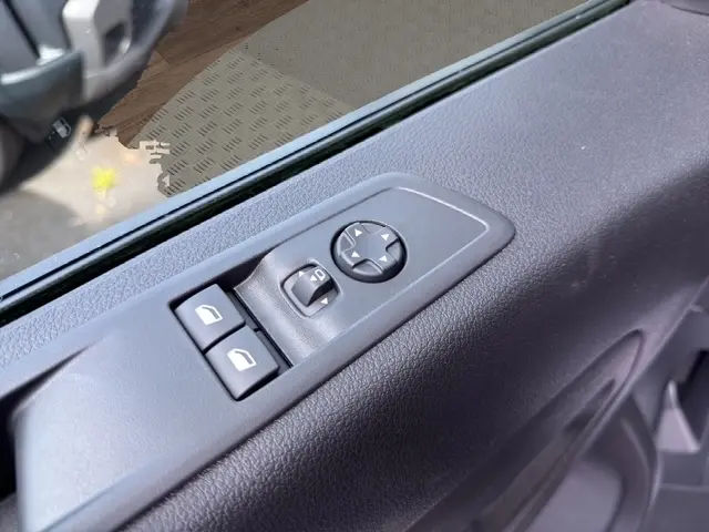 Gros plan sur les commandes électriques des vitres et des rétroviseurs côté conducteur d'un Citroën Jumpy blanc.