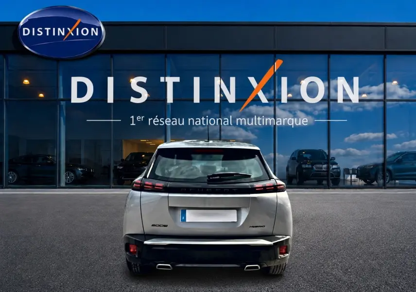 Vue arrière d’un Peugeot 2008 gris 2025 garé devant une vitrine avec logo Distinxion.