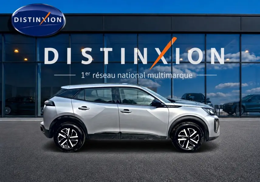 Peugeot 2008 gris en profil droit, avec jantes noires et toit contrasté devant une vitrine Distinxion.