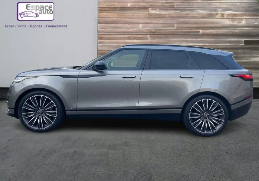 Profil droit d'un Range Rover Velar gris 2019 avec jantes alliage distinctives et toit noir contrastant.