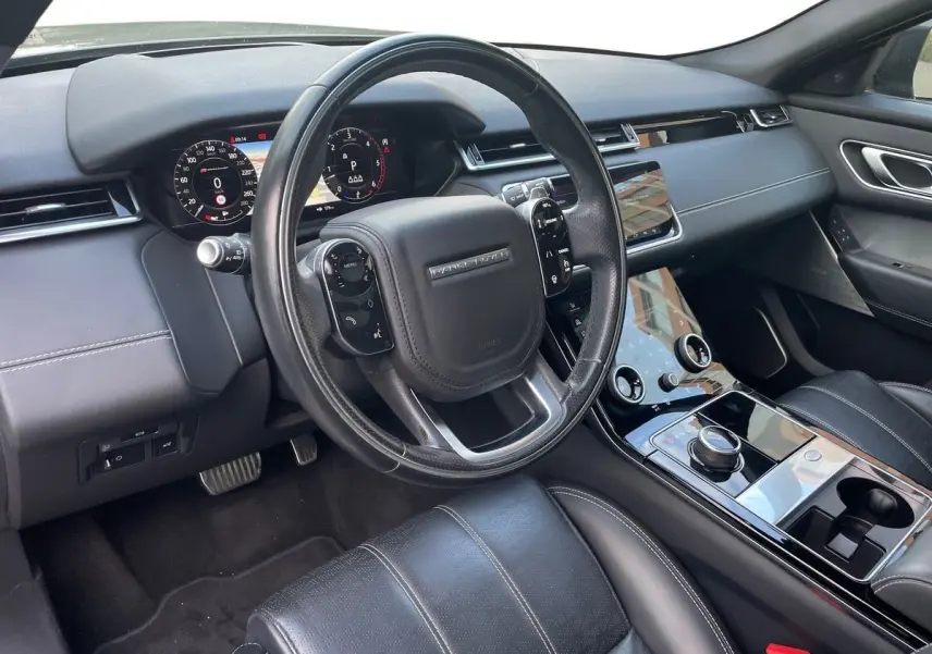 Intérieur noir du Range Rover Velar 2019, vue côté conducteur sur le tableau de bord et la console centrale tactile.