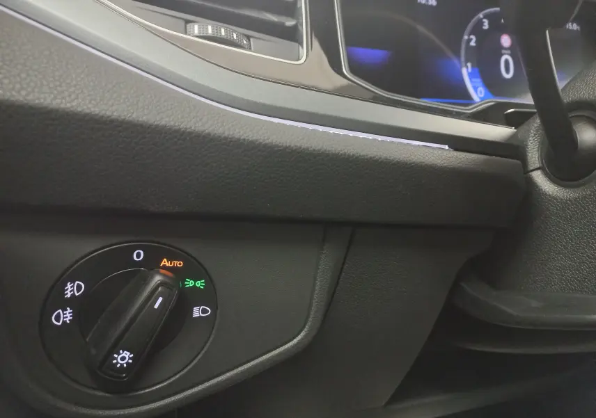 Gros plan sur le tableau de bord noir de la Volkswagen Polo 2025, avec commande d'éclairage et affichage numérique bleu.