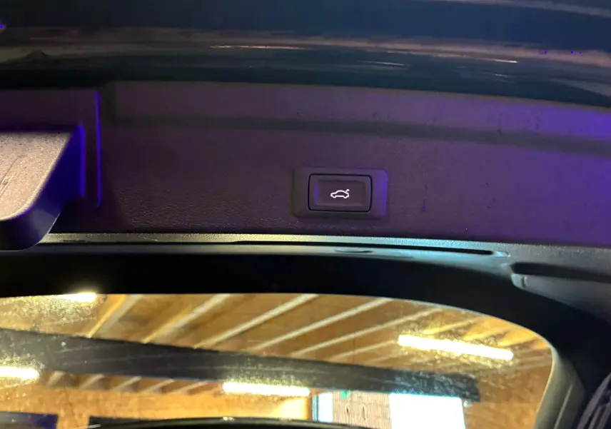 Bouton d'ouverture électrique du coffre visible sur le hayon intérieur d'un Audi Q3 Sportback noir.