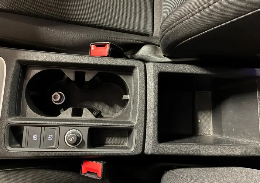 Gros plan sur la console centrale noire de l'Audi Q3 Sportback 2022 avec porte-gobelets et commandes électriques.