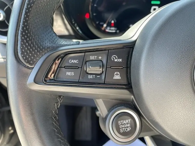 Gros plan sur les commandes au volant et bouton start/stop d’un Alfa Romeo Tonale gris foncé 2023, côté gauche.