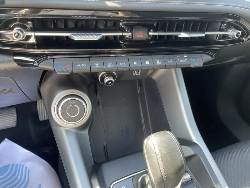 Vue rapprochée de la console centrale de l'Alfa Romeo Tonale 2023, avec commandes climatisation et levier de vitesse en cuir.