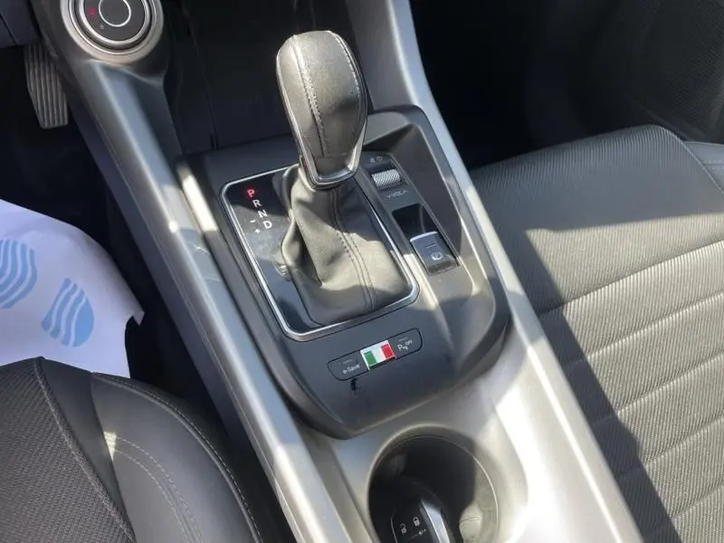 Vue rapprochée de la console centrale de l'Alfa Romeo Tonale 2023, levier de vitesse automatique et badge tricolore italien.