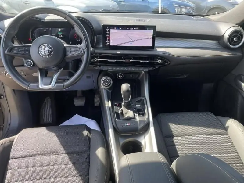 Vue intérieure de l'Alfa Romeo Tonale 2023 montrant le tableau de bord, volant multifonction et écran central tactile.