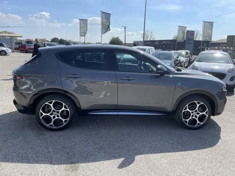 Vue latérale droite d'un Alfa Romeo Tonale gris foncé métallisé 2023 avec jantes distinctives à cinq cercles.