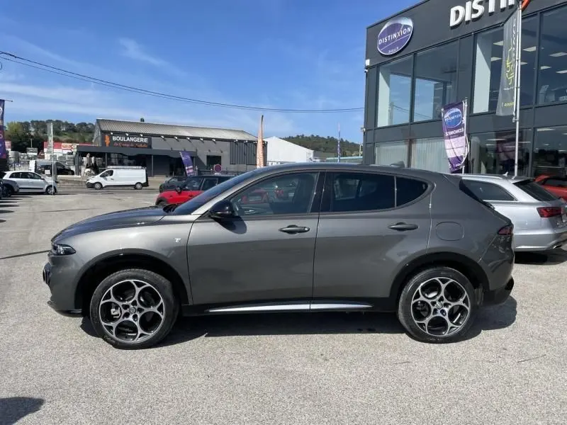 Vue de profil côté gauche d'un Alfa Romeo Tonale gris foncé métal 2023, hybride rechargeable, roues distinctives à cinq cercles.