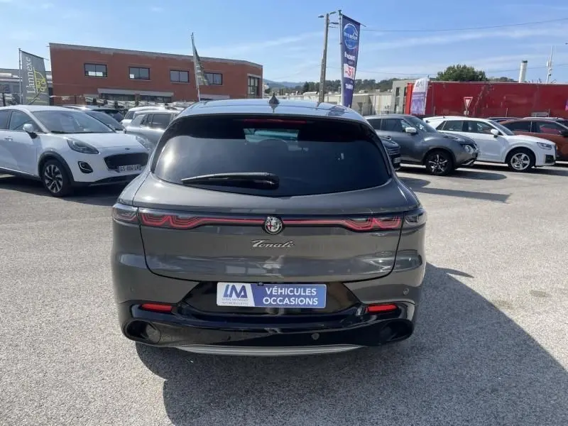 Vue arrière d'un Alfa Romeo Tonale gris foncé métal 2023 avec feux arrière étirés et logo central lumineux.
