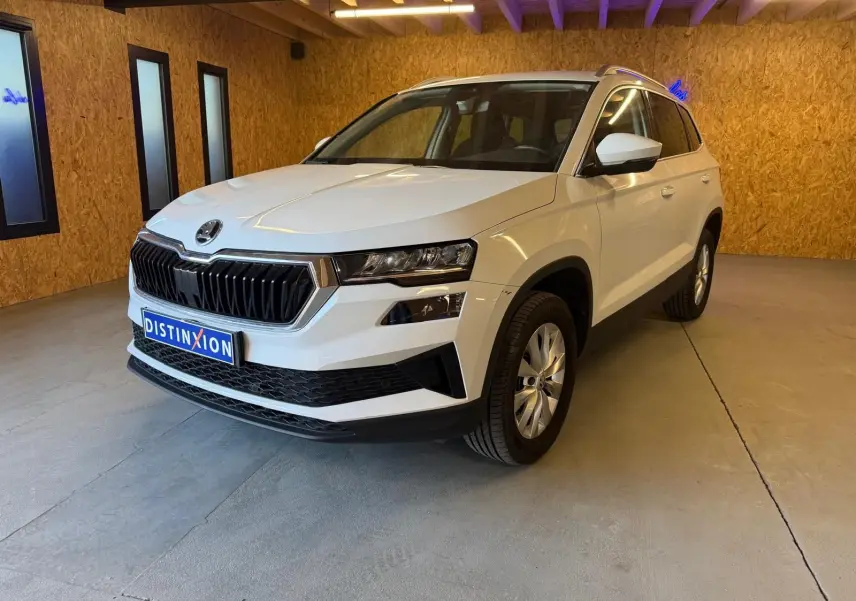 Vue 3/4 avant droite d'un Skoda Karoq blanc 2023 avec calandre noire et jantes alliage en intérieur.